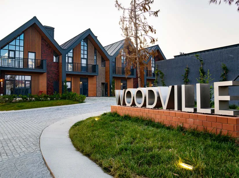 Giriş: kərpic postamentdə WOODVILLE hərfləri